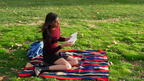 una estudiante universitaria leyendo un libro y relajándose al aire libre en el parque con hojas de otoño y hierba verde