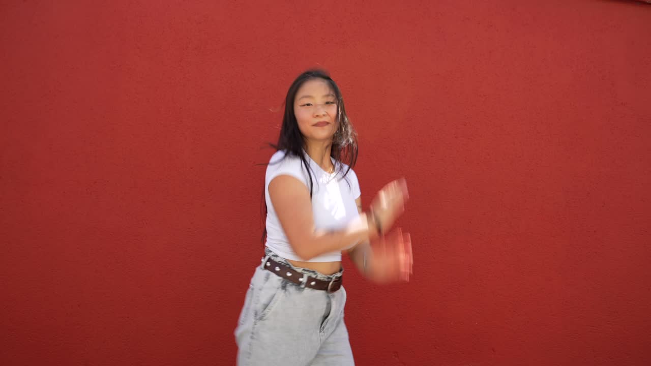 Young woman dancing by red wall