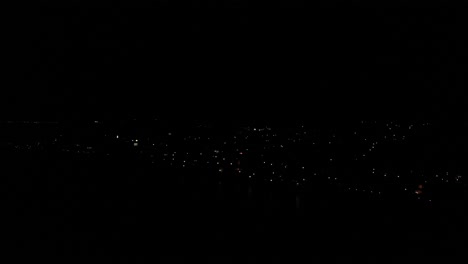 vista aérea sobre el cielo nocturno oscuro sobre la ciudad de estepona con luces de edificios sólo visibles