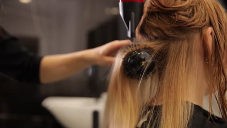 a skilled stylist showcases effective hair drying techniques by utilizing a round brush along with a blow dryer