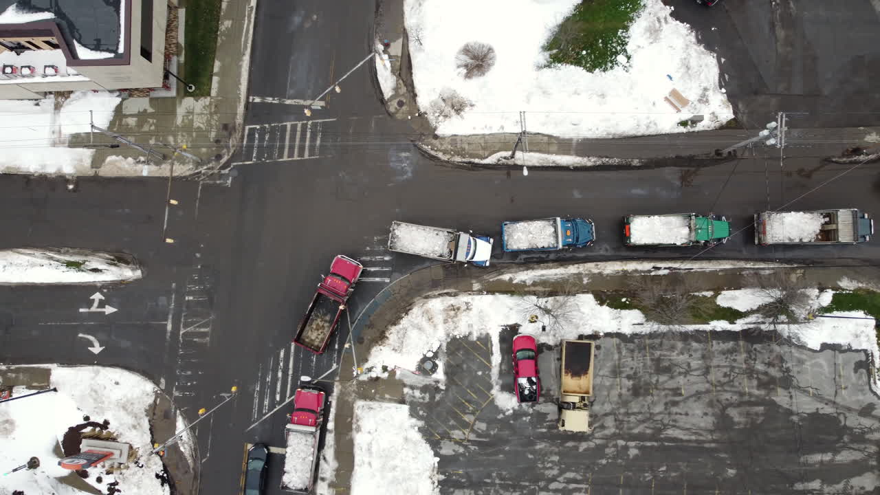 덤프 트럭의 대기열을 보여주는 공중 조감도는 뉴욕 버팔로에 있는 저장 장소로 눈을 운반합니다.