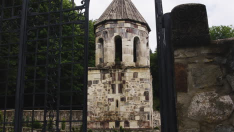 Stone-bell-tower-of-Mtsvane-monastery-behind-open-iron-railing-gate