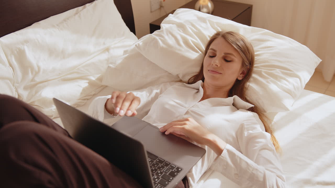 침대에 노트북으로 일하는 여자