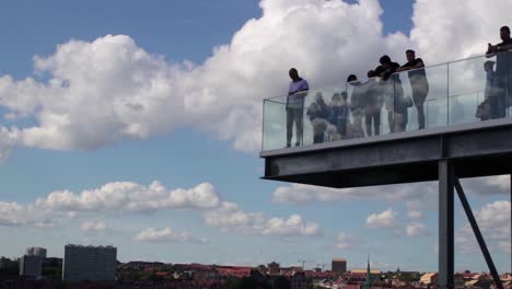 people on an observation deck overlooking a city under a cloudy sky