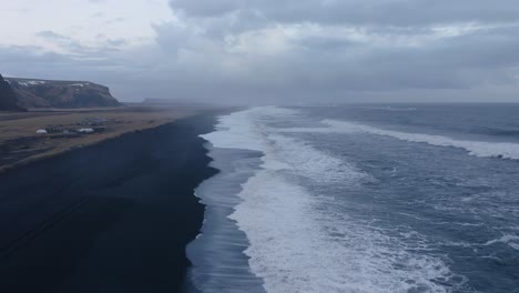 Volando-Hacia-Un-Tramo-De-Playa-De-Arena-Negra-Con-Olas-Tormentosas-En-Víkurfjara-Cerca-De-Vik-En-Islandia