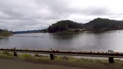 Driving-by-a-river-with-pilings-sticking-out-of-the-water-that-where-used-for-logging,-floating-logs-down-the-river,-and-tie-them-up