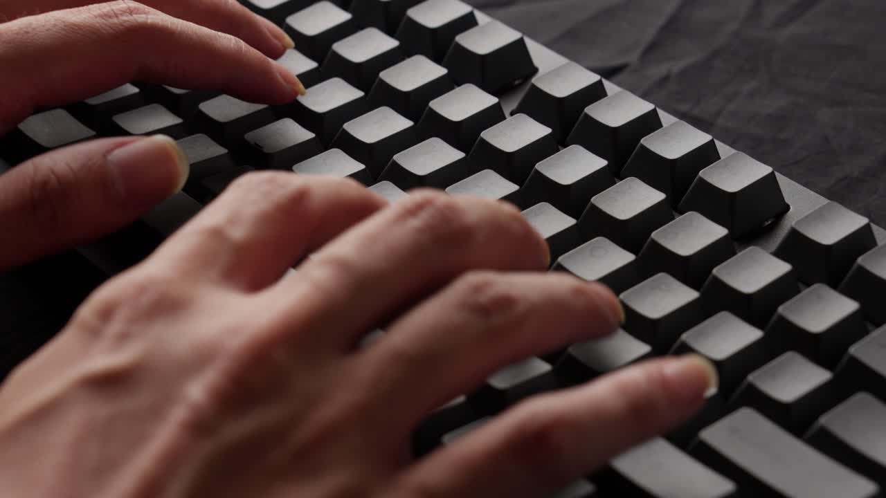 Hands of a man typing text on a mechanical keyboard without printed letters
