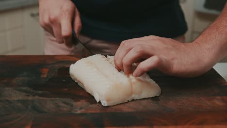 slicing white fish meat on wooden cutting board