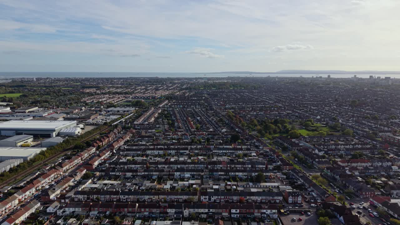 Droneflyvning over Portsmouth, Storbritannia, over omfattende rekkehus nær havnen med sjøen i det fjerne på en lys dag.