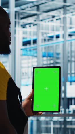 vertical video worker using green screen laptop in smart factory, collecting and analyzing data