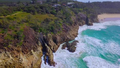 tilting aerial view of wild rocky coastline with turquoise blue water and sea foam