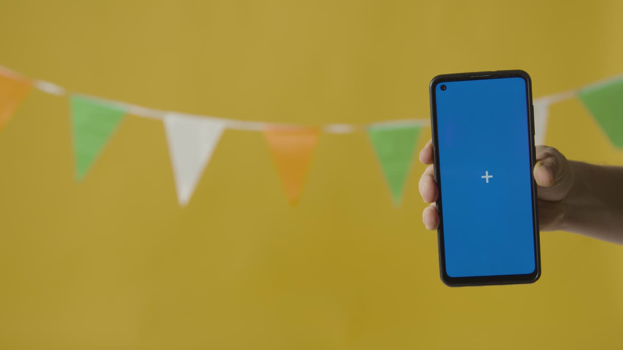 Blue Screen Mobile Phone Against Bunting In Colours Of Irish National Flag Hung In Studio To Celebrate St Patricks Day 1