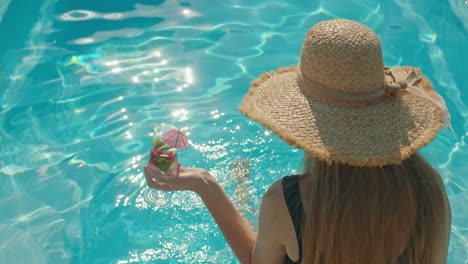 mujer relajándose junto a la piscina con un cóctel