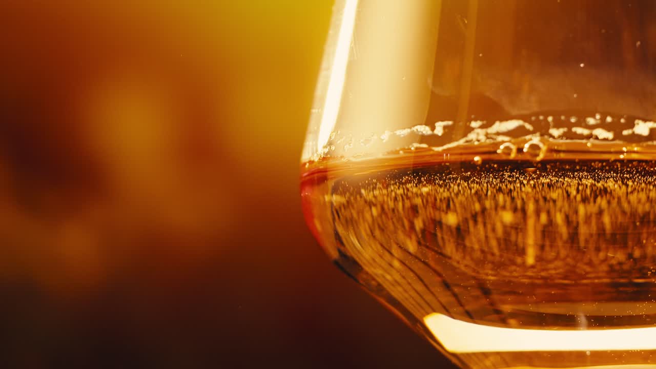 Orange or white wine bottle and glass against a sunset in a peaceful vineyard, pouring of ecological natural wine.