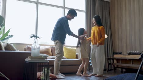 happiness sunday morning dad mom and daughter spending wonderful moment dancing along together,asian family father mother and daughter jump dance cheerful moving together in living room at home