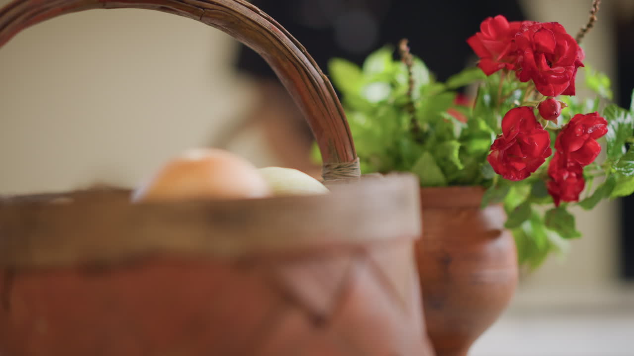 Basket and vase with red flowers, soft focus background, wicker basket with onions, warm morning light, intimate kitchen scene, inviting mood for home cook preparing meal, shallow depth of field