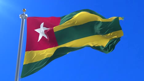 Togo flag waving at wind in slow with blue sky, loop