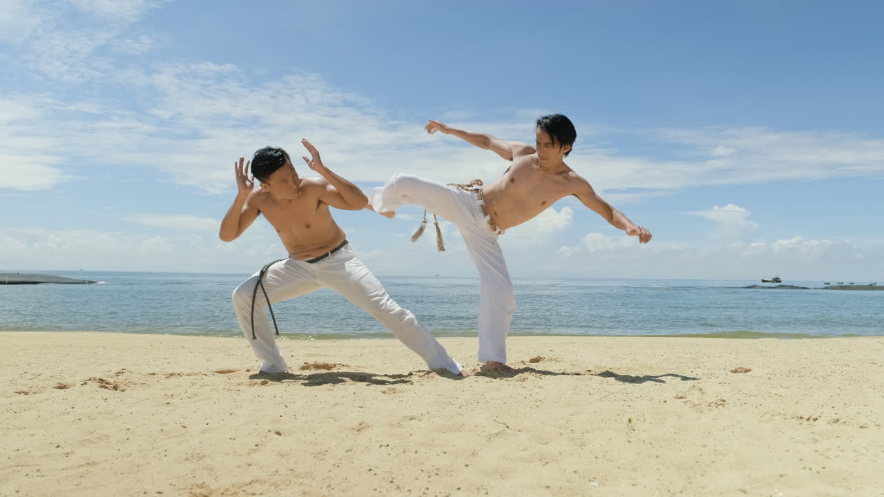 dos hombres bailando capoeira en la playa