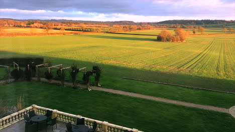 leicestershire manor house diagonally overlooking golden field with courtyard with alfresco setting and stone fence