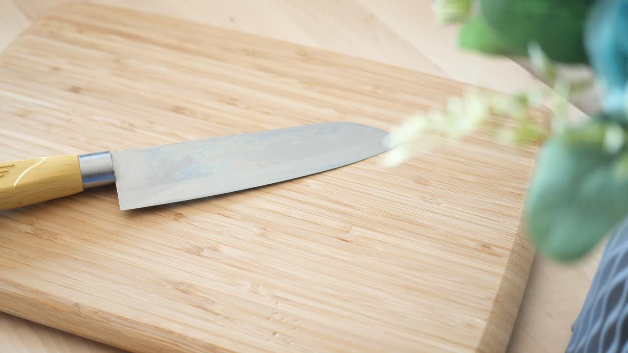 un cuchillo de mango amarillo descansando en una tabla de cortar de madera