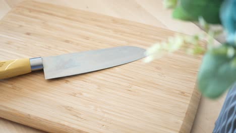 a yellow handled knife resting on a wooden chopping board