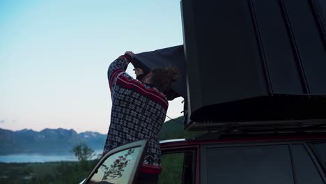 portrait of a hiker setting car roof tent at sunset nature