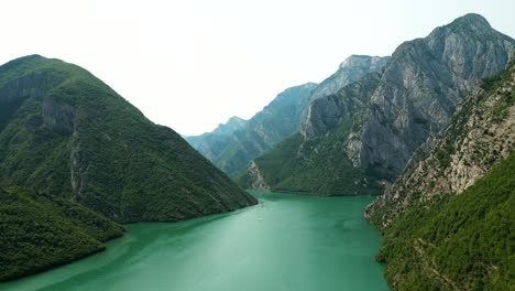 Albania,-the-green-waters-of-Lake-Koman-nestled-among-the-slopes-of-the-Accursed-Mountains,-aerial-view-from-a-drone