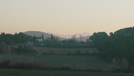 house in green field valley during misty early morning