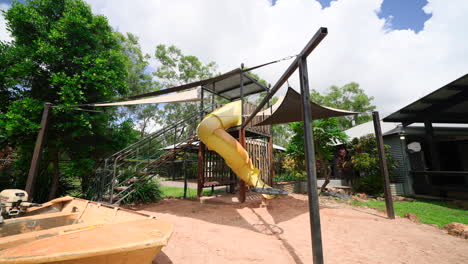 Parque-Infantil-De-Lujo-Con-Sombrilla-Que-Cubre-El-Tobogán-En-Un-Foso-De-Arena-Con-Bote-En-El-Patio-Trasero-De-Una-Elegante-Casa-Tropical-En-Grandes-Terrenos-Rurales