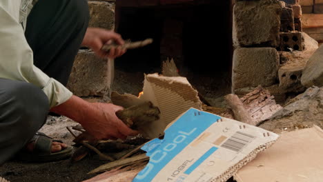 tight close up of potter feeding cardboard to start fire than ha hoi an vietnam