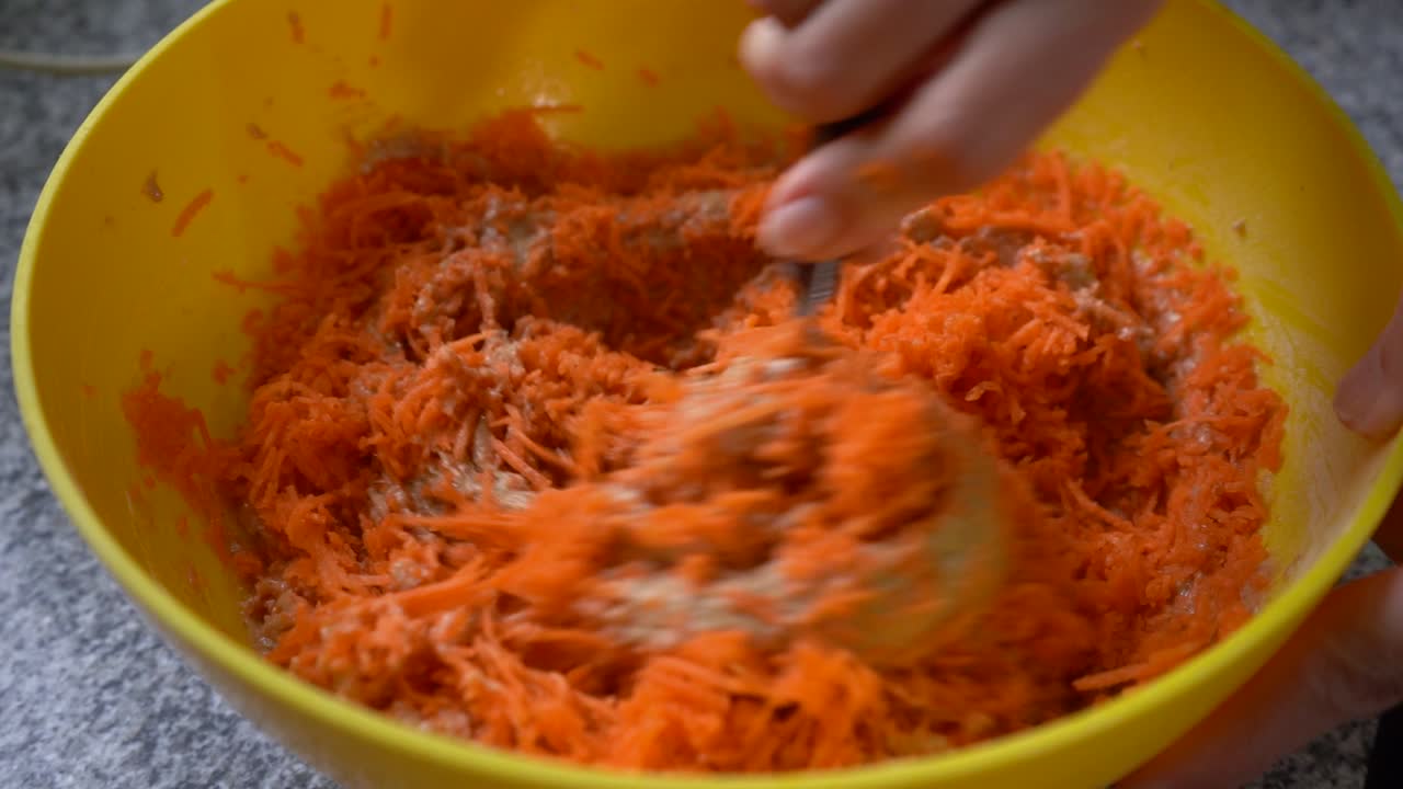 Misturando massa de bolo de cenoura em tigela com farinha integral e cenoura ralada.