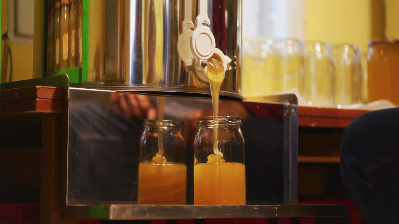 verter miel de acacia en una jarra en el apiario