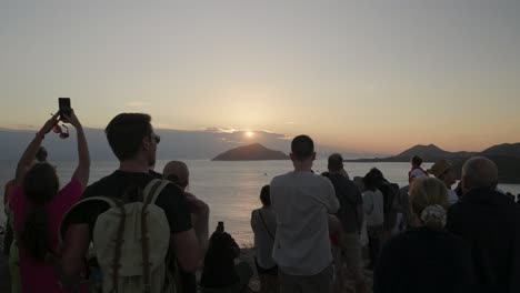 group of tourists overlooking sunset at cliffs with ocean