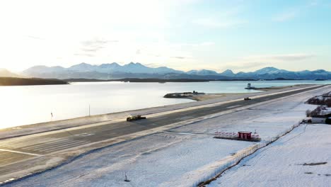 plow trucks remove snow from the runway at molde airport, årø, norway