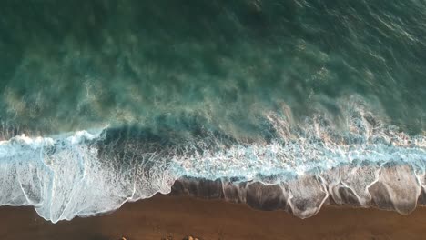 Sea-waves-at-the-beach,-top-fixed-aerial-view-over-sea-waves-splashing-to-the-coastline-shores-captured-during-daytime