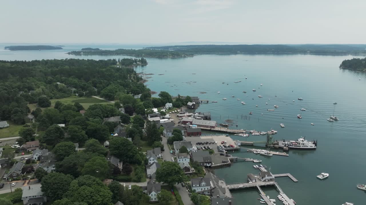 Aerial view of North Haven, Maine, showcasing a charming coastal village, boat-filled harbor, and surrounding forested islands on a calm summer day.