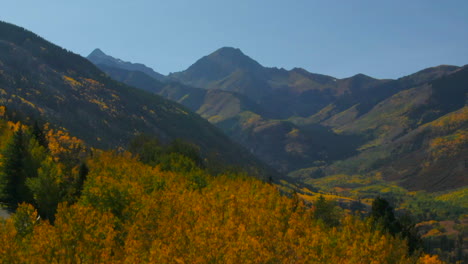 colorado summer fall autumn colors aerial drone cinematic aspen snowmass mountain maroon bells pyramid peak beautiful stunning blue sky mid day sunny reveal past yellow trees upward movement