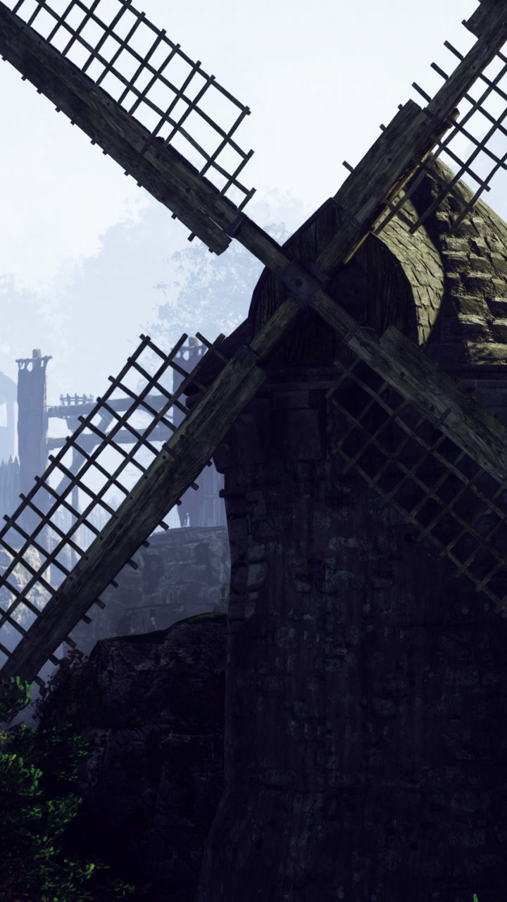 Historic windmill stands tall among misty hills at dawn
