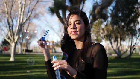 A-young-woman-blowing-bubbles-floating-in-the-sunlight-while-laughing-and-smiling-happily