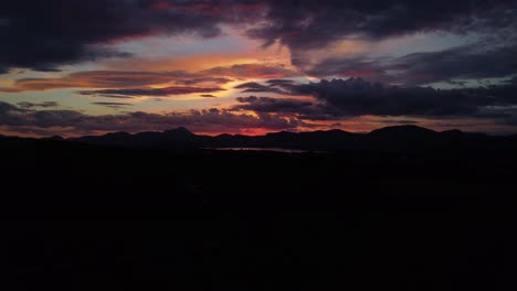 Drohnenaufnahme-Des-Späten-Sonnenuntergangs-über-Feldern-Und-Bergen-Mit-Dramatischem-Himmel