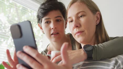 Mujer-Caucásica-Sonriendo-Mientras-Hace-Una-Videollamada-En-Un-Teléfono-Inteligente-En-La-Cocina-De-Casa