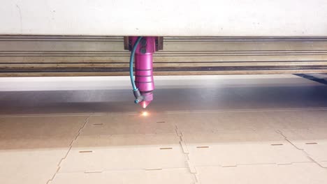 modern technological industrial laser cnc while cutting a pattern on a plywood sheet and moving slowly, close up