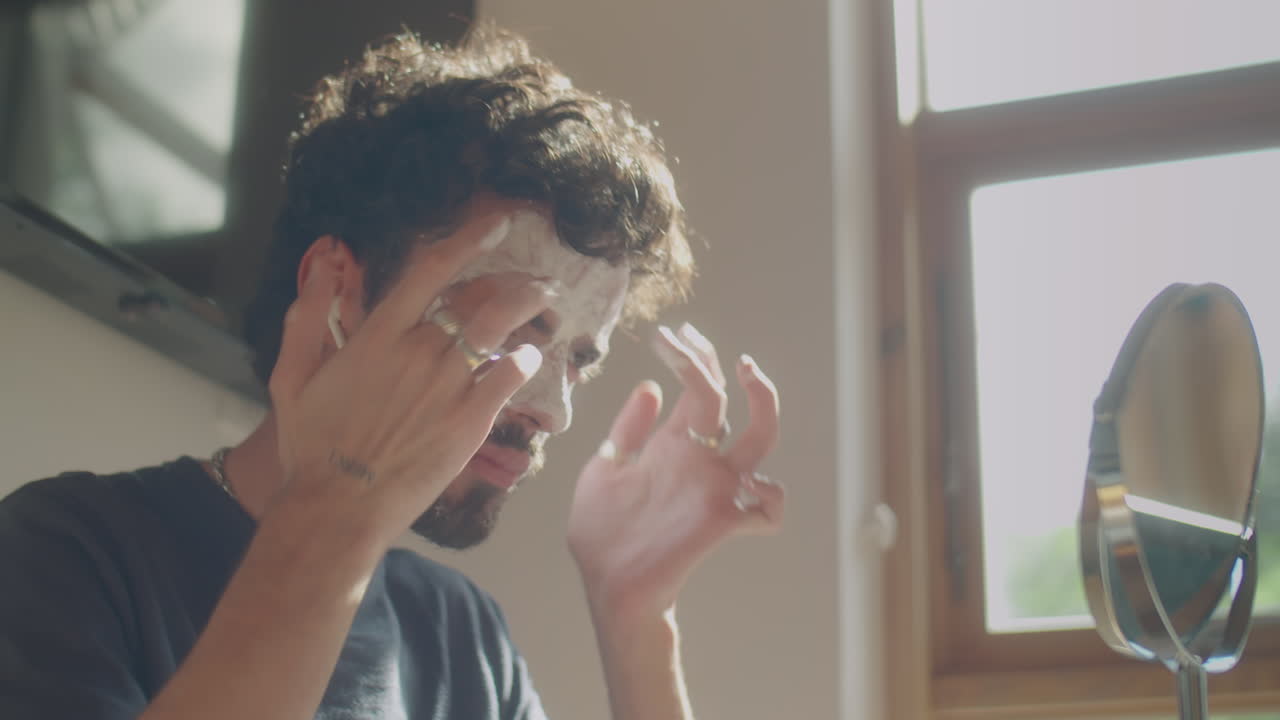 Man Applying Face Mask and Listening to Music at Home