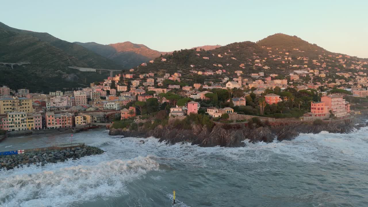 Grandi onde marine che si infrangono sulla costa rocciosa del porto con case, Genova