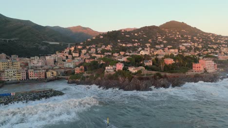 grandes olas del mar rompiendo en la costa rocosa del puerto con casas, ciudad de génova