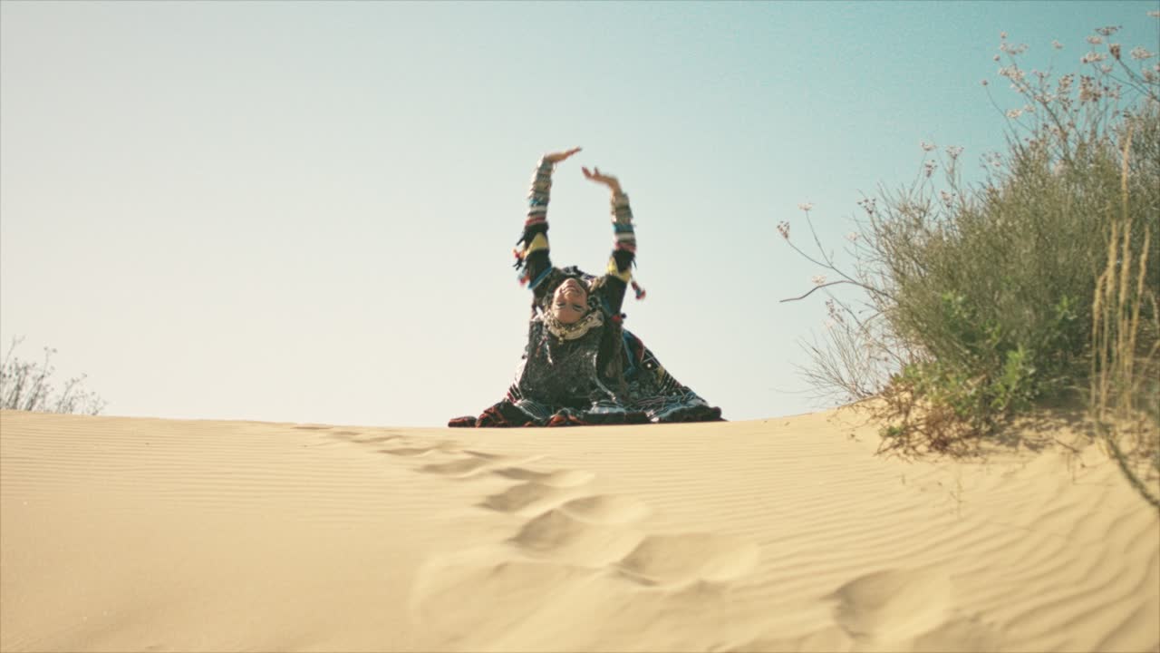 사막의 모래 언덕에서 손을 흔드는 집시 여성