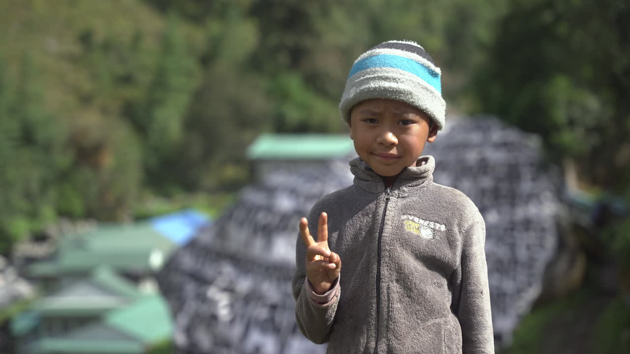 A male child on the way to Everest Base Camp trekking smiles and poses in front of camera with awe and innocence, people of Himalayas, a peaceful retreat on landscapes and lap of nature