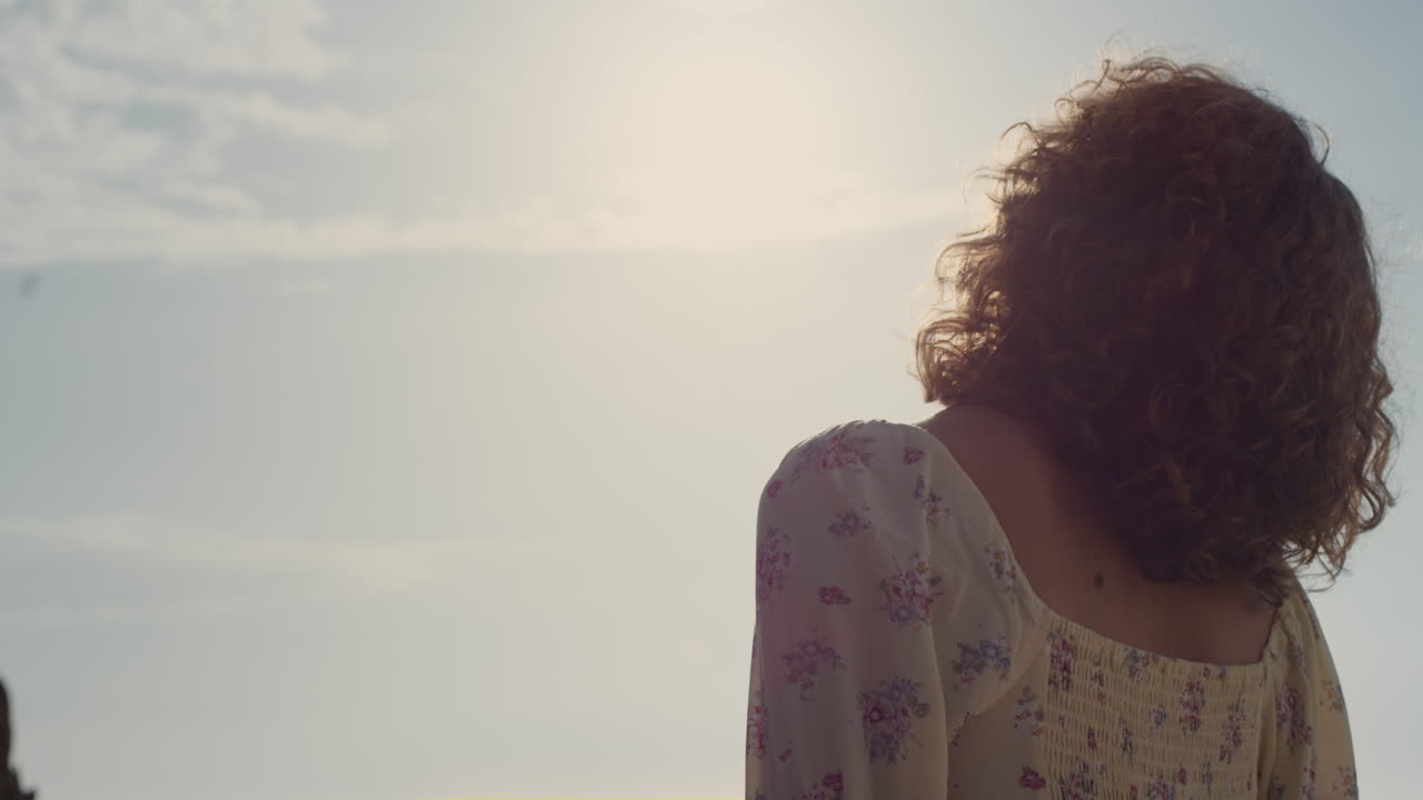 Primo piano di donna sconosciuta che alza il viso verso la luce del sole. Ragazza di spalle in piedi da sola.
