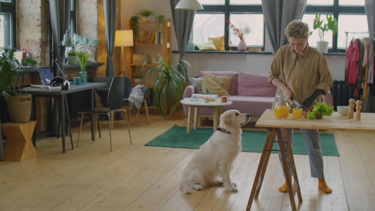 Girl with Prosthetic Arm Treating Dog while Cooking Meal