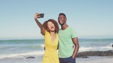 una pareja afroamericana tomando una selfie en la playa